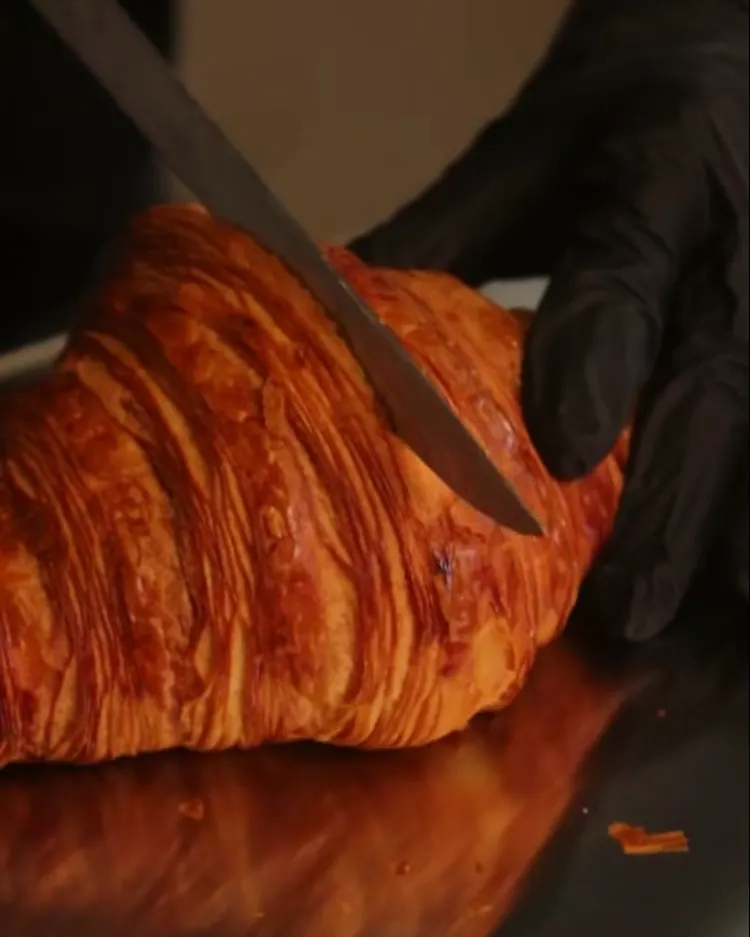Corte de croissant: el cuchillo entra y deja ver sus capas de hojaldre