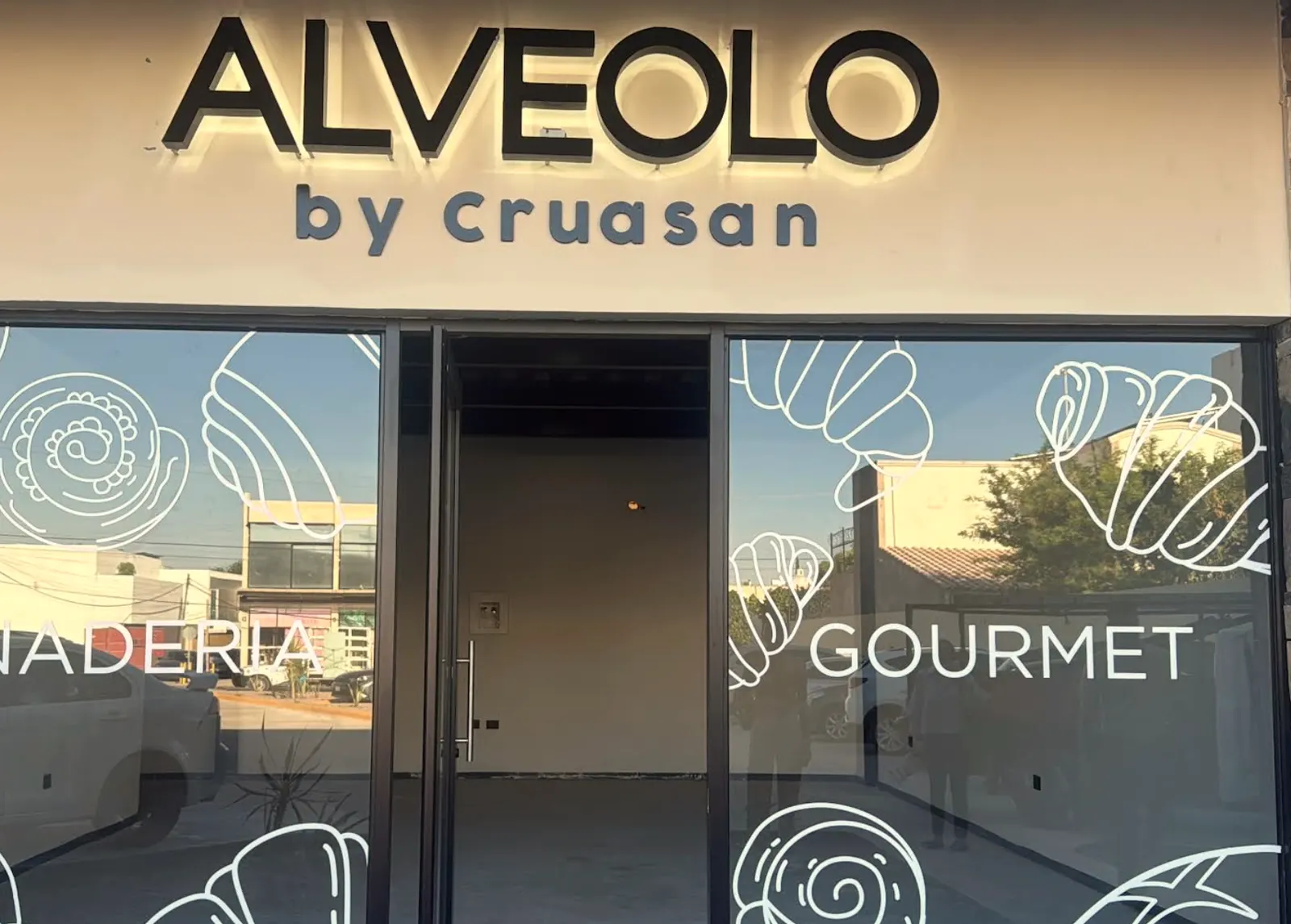 Fachada de la sucursal en Federico García Lorca, con el letrero iluminado y los ventanales decorados con dibujos de pan